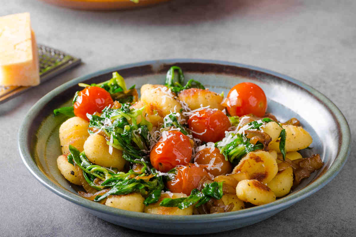 piatto con gnocchi ricchi di condimento con sugo di pomodoro e rucola