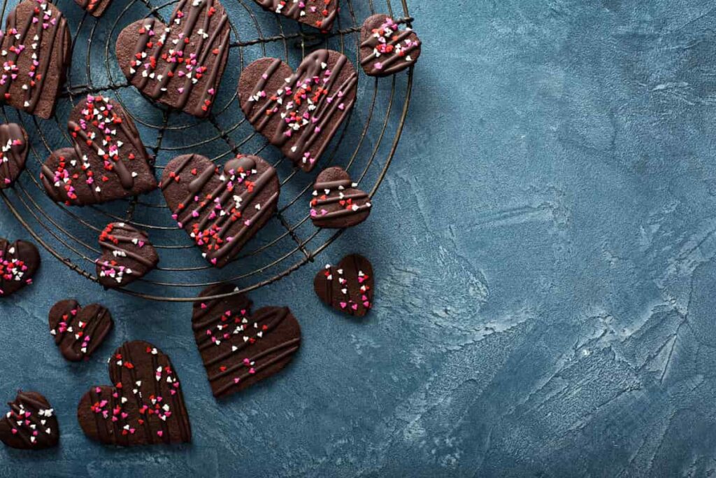 biscotti a forma di cuore per San  Valentino gallati con cioccolato e zuccherini colorati