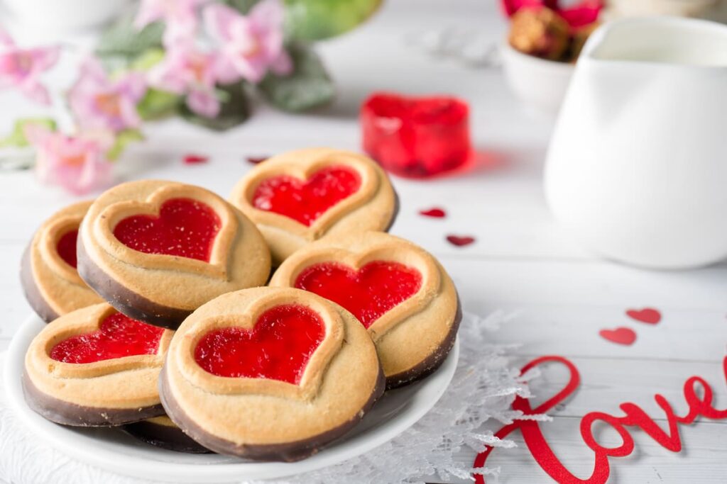 vassoio con biscotti  di San Valentino con cuoricino ripieno di marmellata accanto scritta love 
