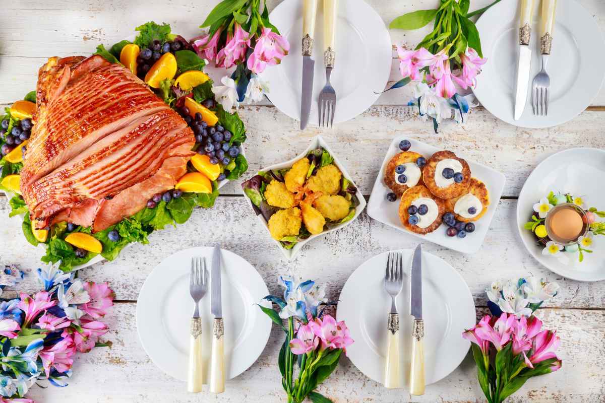 tavola apparecchiata per il pranzo di pasqua con portate e fiori freschi