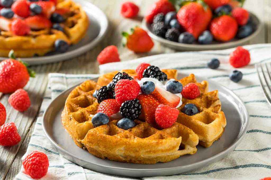 piatto rotondo basso con waffle classici con frutta fresca, frutti di bosco: lamponi, more, mirtilli e fragole