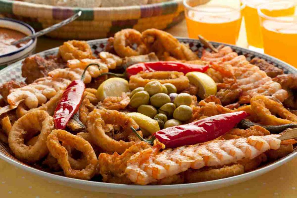 menu prima comunione, tavola imbandita con antipasti, primi, secondi e dolci con primo piano su un piatto di pesci misti