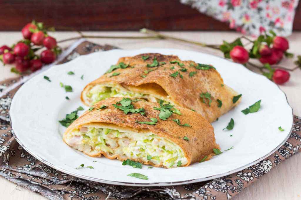 crespelle con zucchine o crepes alle zucchine in piatto bianco