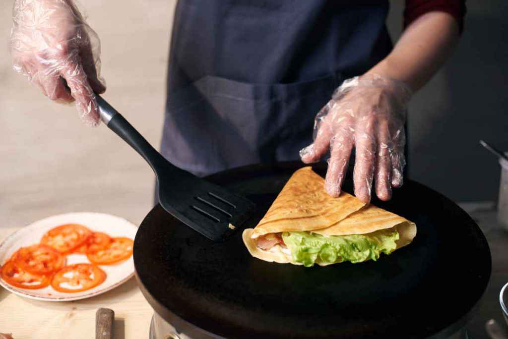 uomo cucina le crepes salate sulla crepiera elettrica