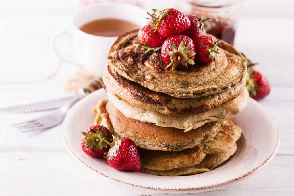 piatto con torretta di pancake proteici senza uova e yogurt con farina di avena e fragole per decorazione