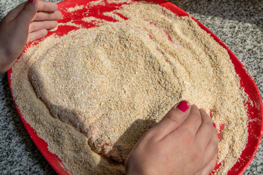 donna mentre prepara le cotolette panate