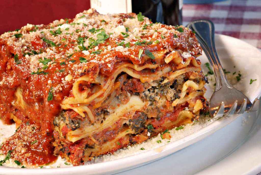 porzione di lasagne ai funghi con sugo di pomodoro