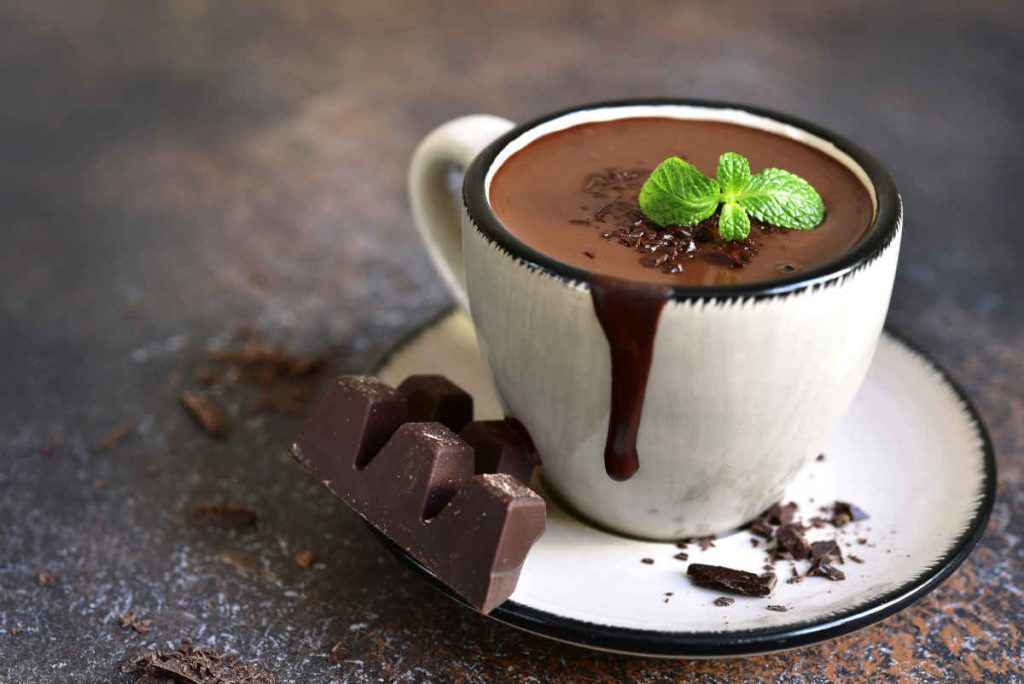 cioccolata calda in tazza bianca con foglie di menta