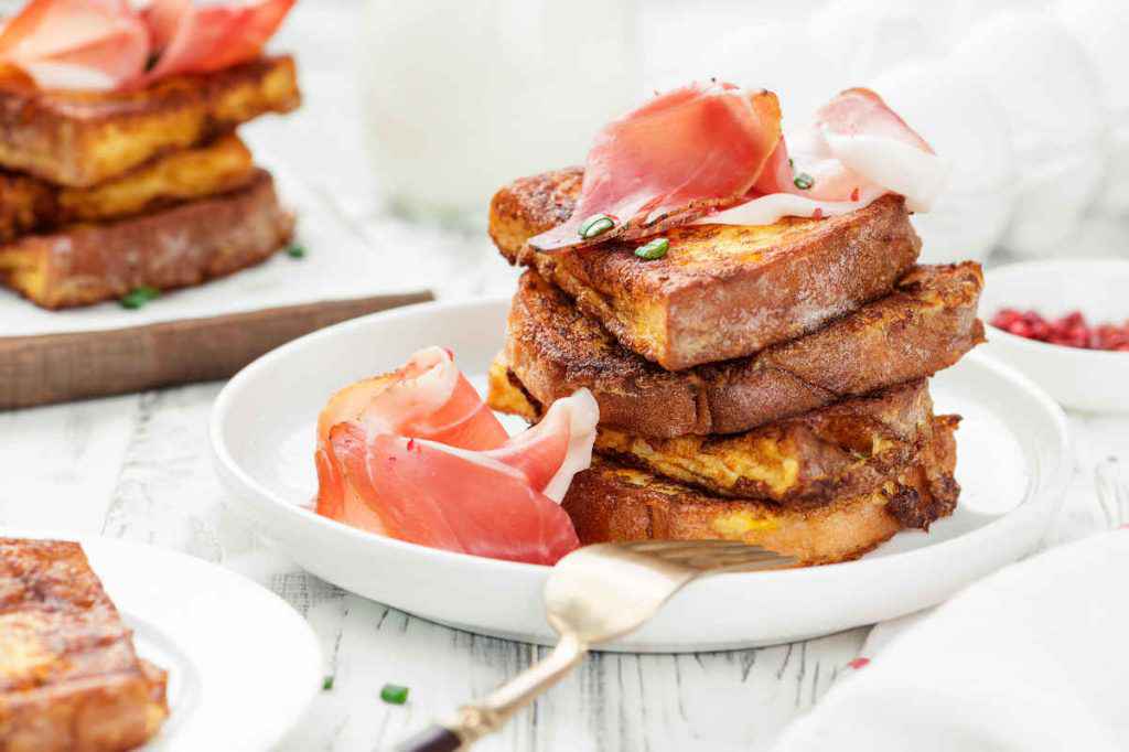 porzioni di french toast al prosciutto su piatto bianco da servire per la colazione a letto salata