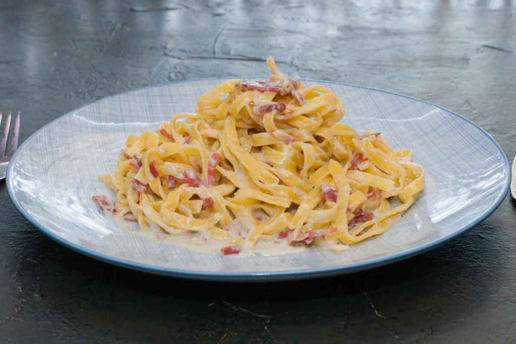 porzione di tagliatelle con mele, speck e salsiccia