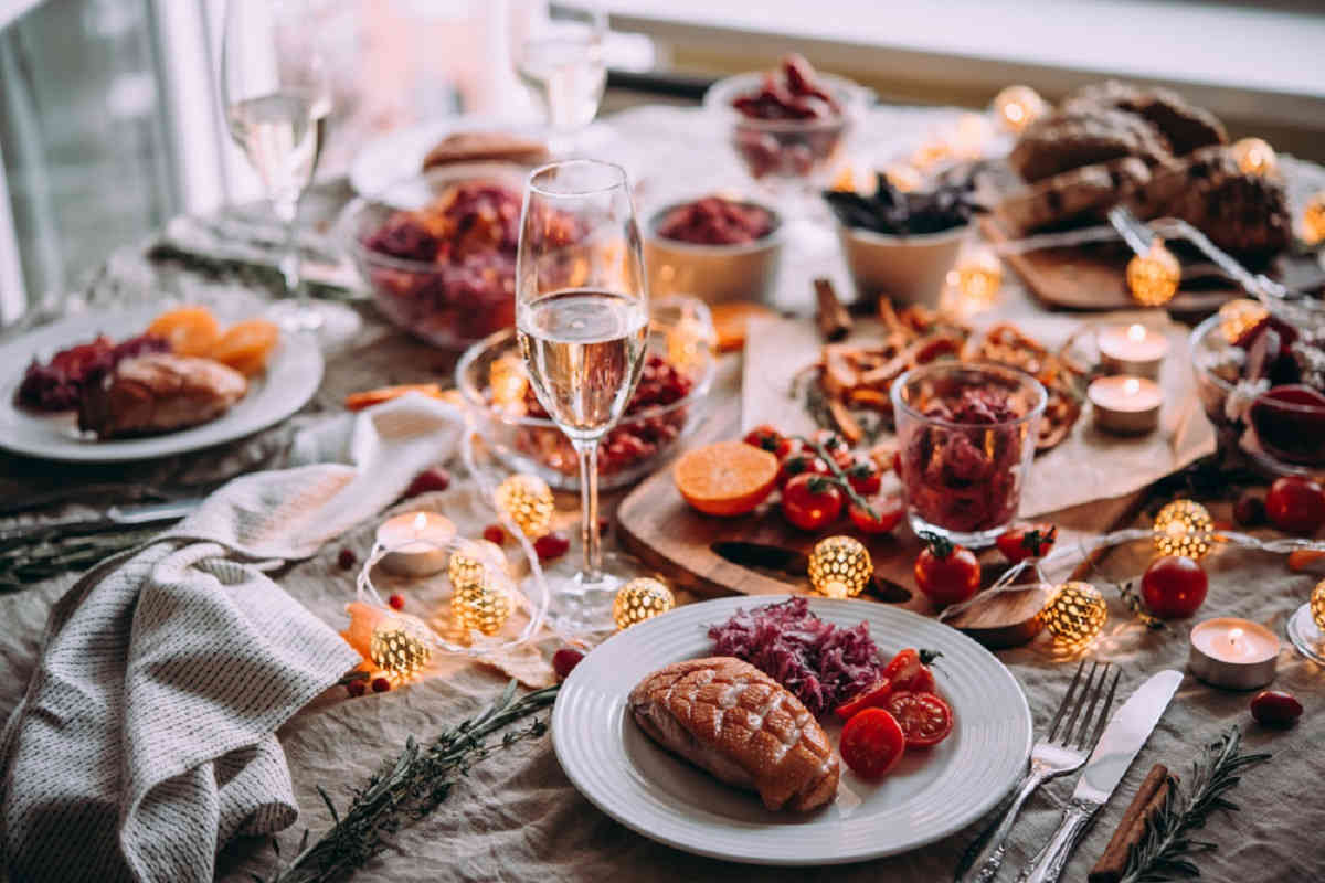 tavola apparecchiata per il cenone di fine anno e piatti con ricette per menu di capodanno