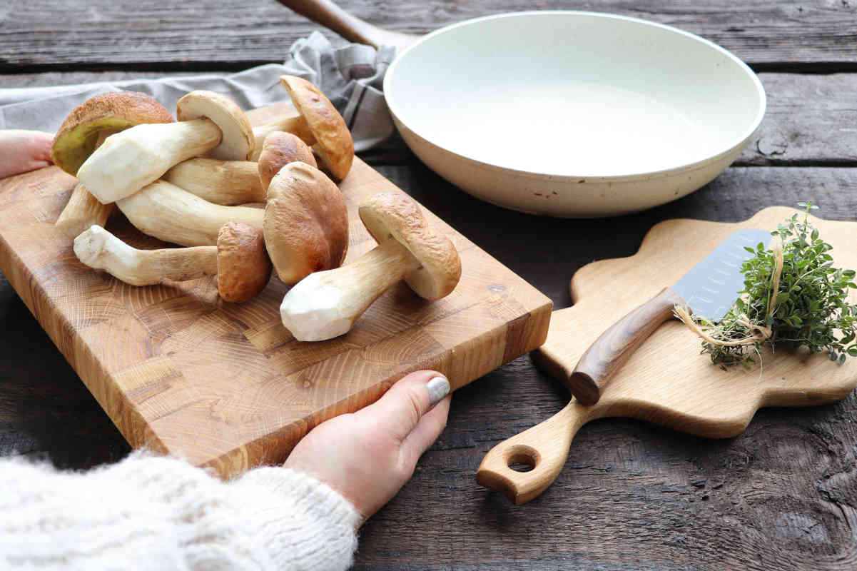funghi porcini su tagliere di legno con erbe aromatiche