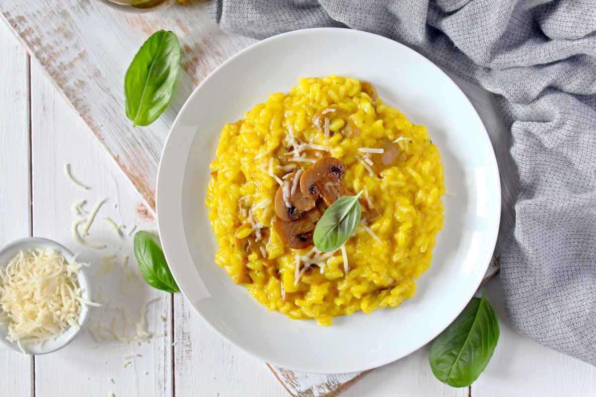 piatto con porzione di risotto cremoso con funghi parmigiano e zafferano