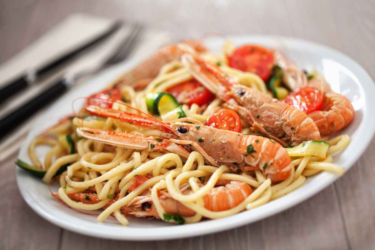 piatto di spaghetti con scampi zucchine e pomodori