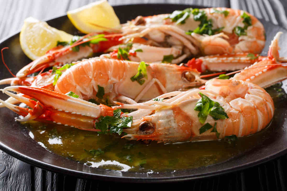 piatto nero con scampi cotti al forno e spicchi di limone