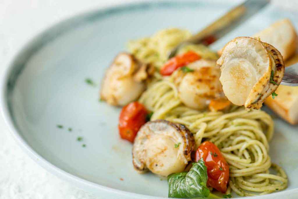 piatto di spaghetti con capesante e pomodorini