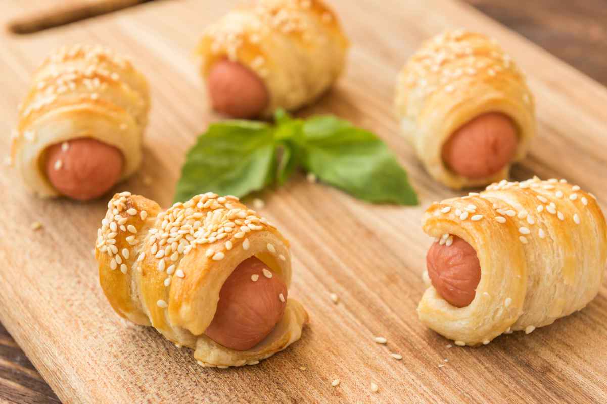 tagliere di legno con antipasti di pasta sfoglia con wurstel