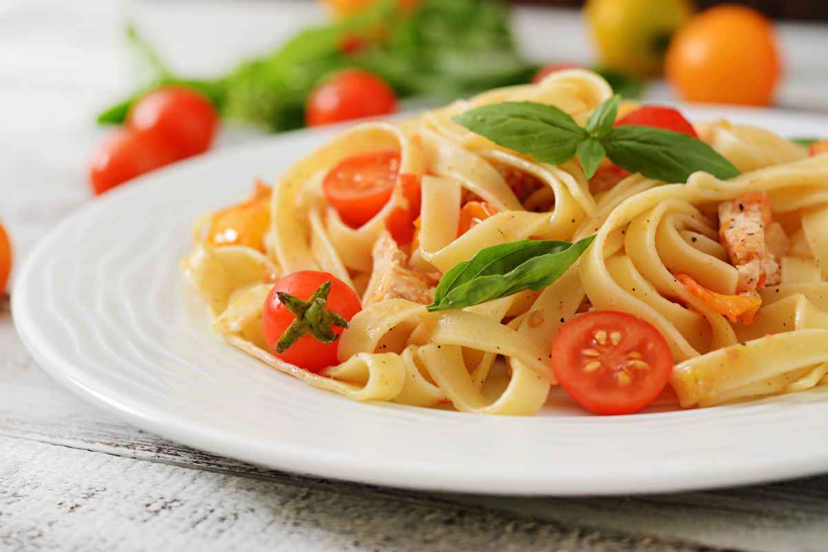 piatto di fettuccine al pomodoro e foglie di basilico
