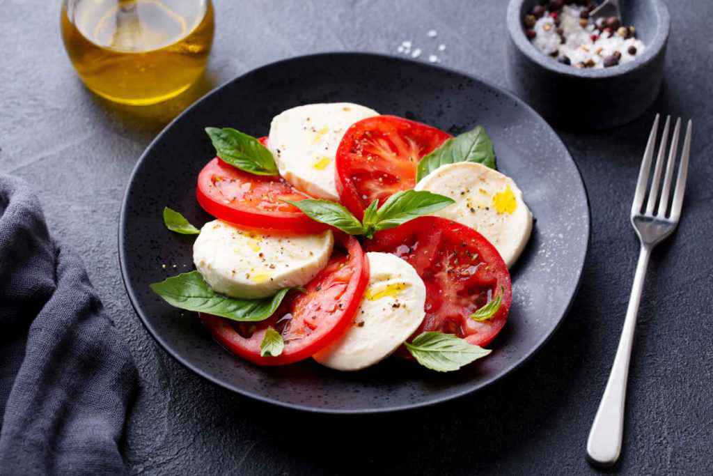 piatto nero con caprese con mozzarella e pomodoro