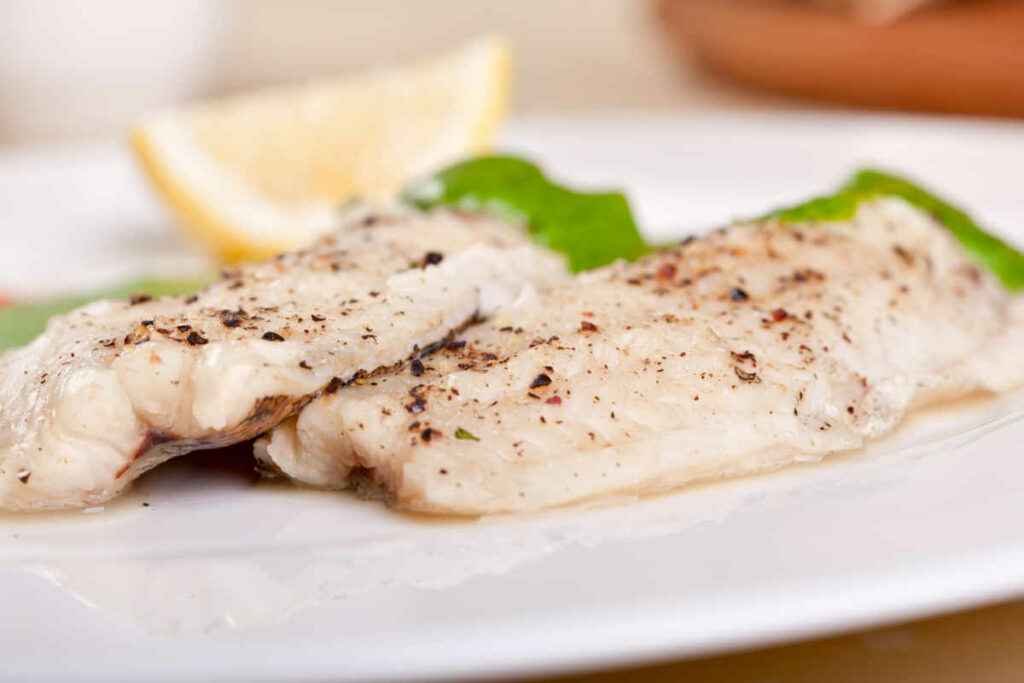 piatto con due filetti di pesce capone gallinella in padella in bianco con limone