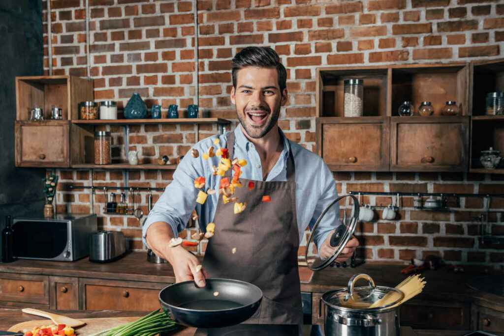 ragazzo con padella in mano cucina la ricetta del giorno