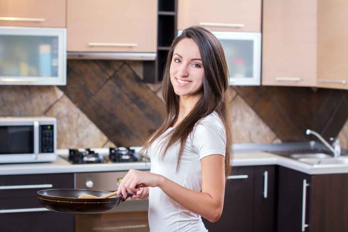 ragazza cucina la ricetta del giorno con la padella in mano