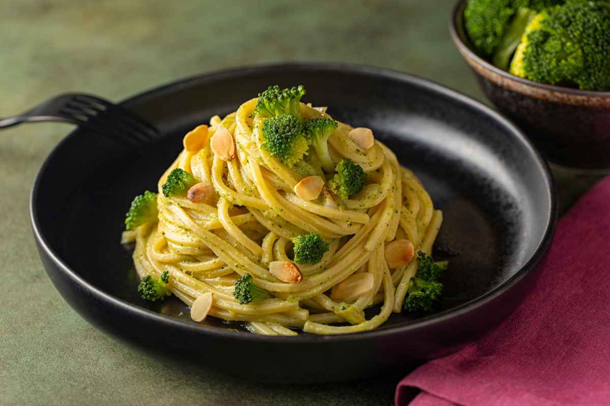 piatto nero con spaghetti alla chitarra al sugo di broccoli e mandorle tostate