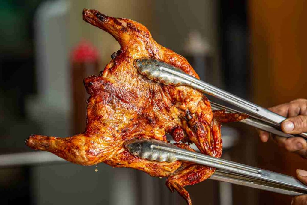 pinze reggono un pollo arrosto