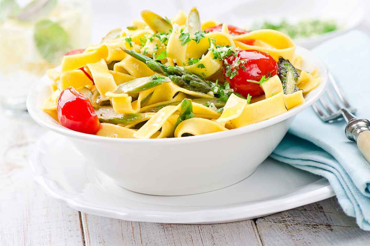 scodella di pasta tipo tagliatelle con pomodori e asparagi