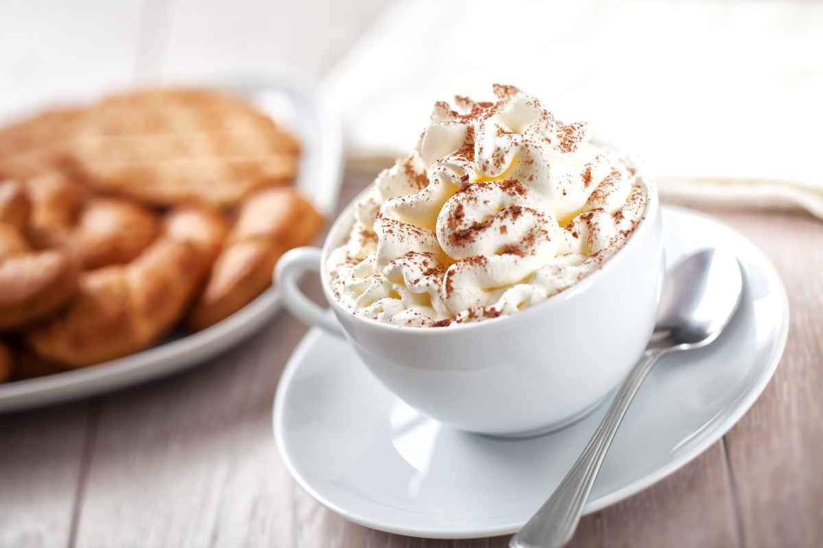 primo piano su una tazza con crema chantilly e cannella