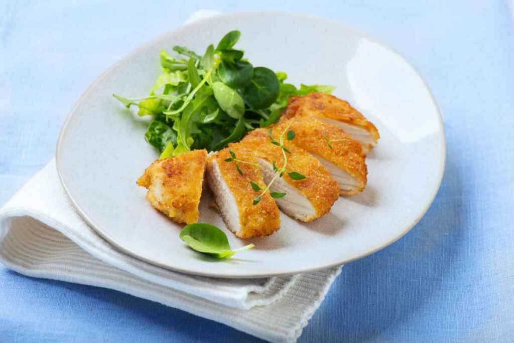 piatto con cotoletta di pollo panata tagliata a fette