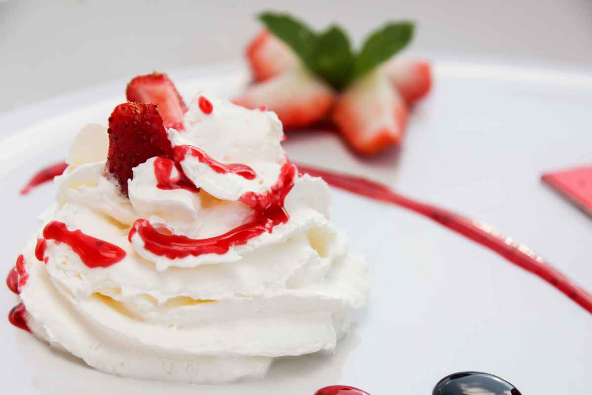 piatto con ciuffo di crema chantilly e salsa di fragole