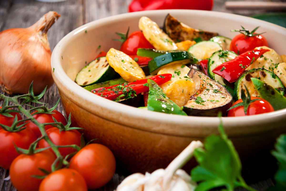 ciotola con contorno a base di patate peperoni e zucchine cotti in padella