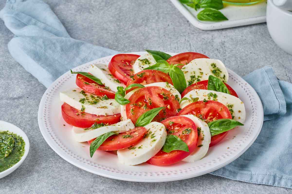 piatto di pomodori e mozzarella caprese con il pesto