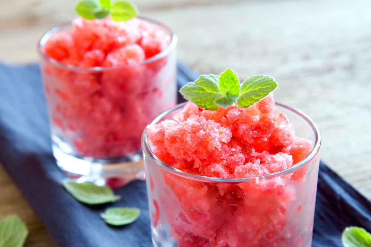 2 bicchieri colmi di granita di frutta mista con foglia di menta