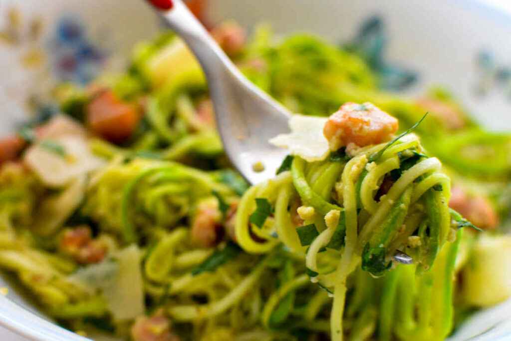 forchetta con spaghetti conditi con crema di zucchina e guanciale fritto