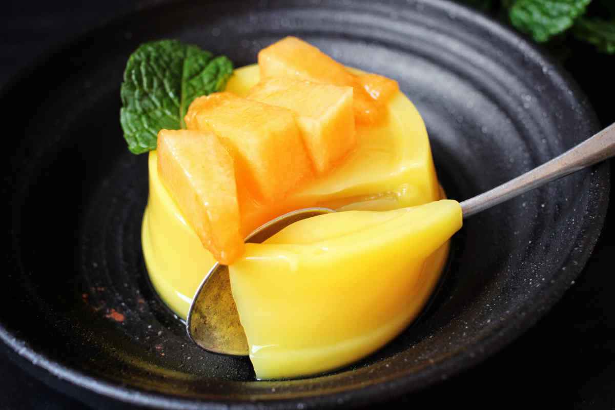 piatto nero con budino al melone decorato con foglie di menta