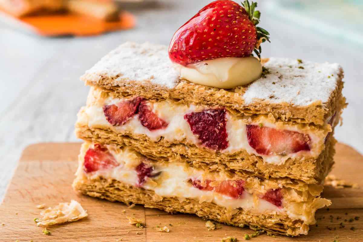 vassoio con fetta di torta millefoglie farcita con crema pasticcera e fragole a pezzi