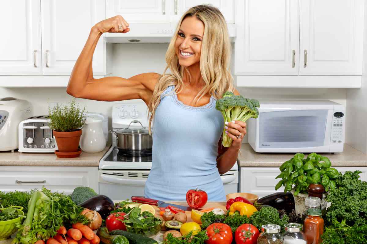 donna mostra i muscoli mentre prepara ricette fit