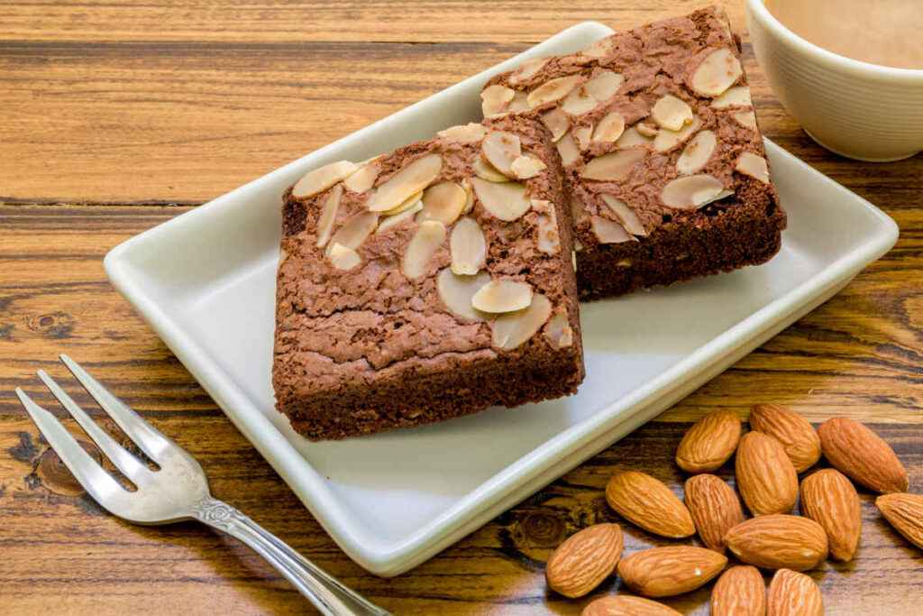 vassoio rettangolare in ceramica bianca con fette di torta proteica al cioccolato e mandorle