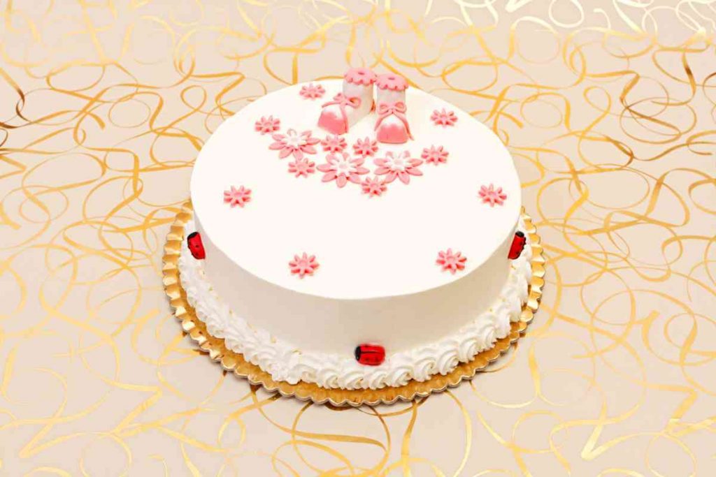 tavola allestita con decorazioni e torta di battesimo con la panna