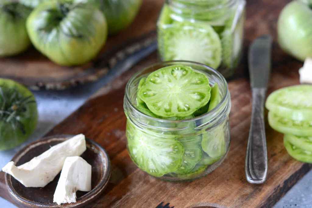 Barattoli di vetro con fette di pomodori verdi sott'olio