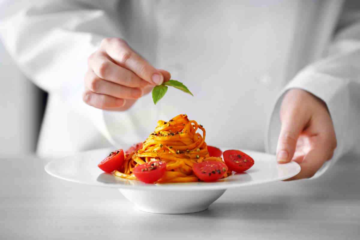 chef sistema il basilico sul piatto di pasta al pomodoro