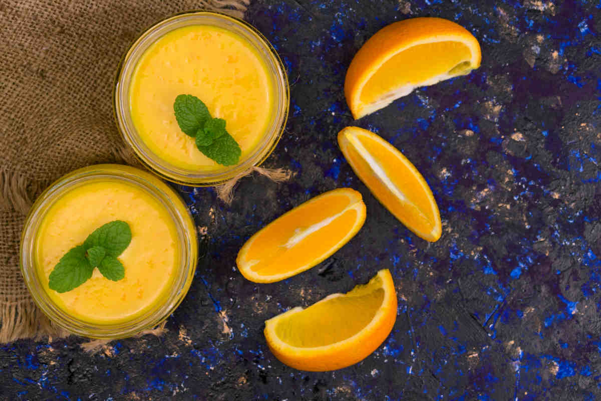 coppette con mousse all'arancia e fettine di arance su tavolo colore blu