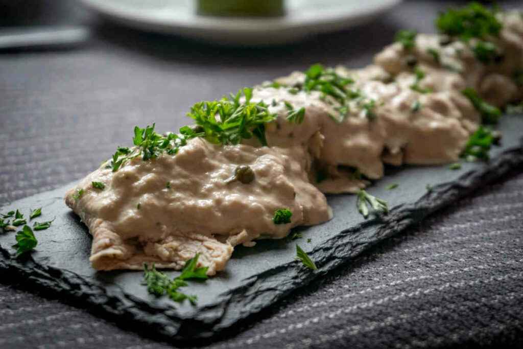 vassoio di ardesia con fette di vitello e salsa tonnata