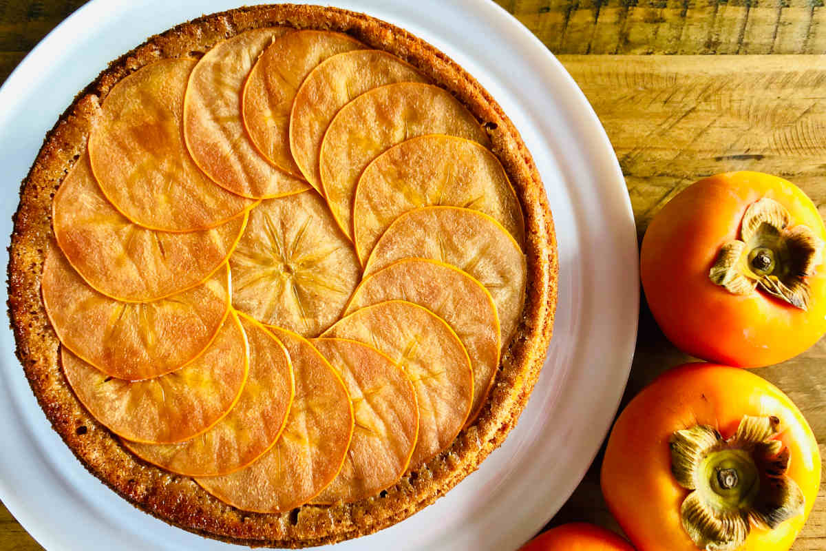 vassoio con crostata ai cachi e vicino dei frutti interi