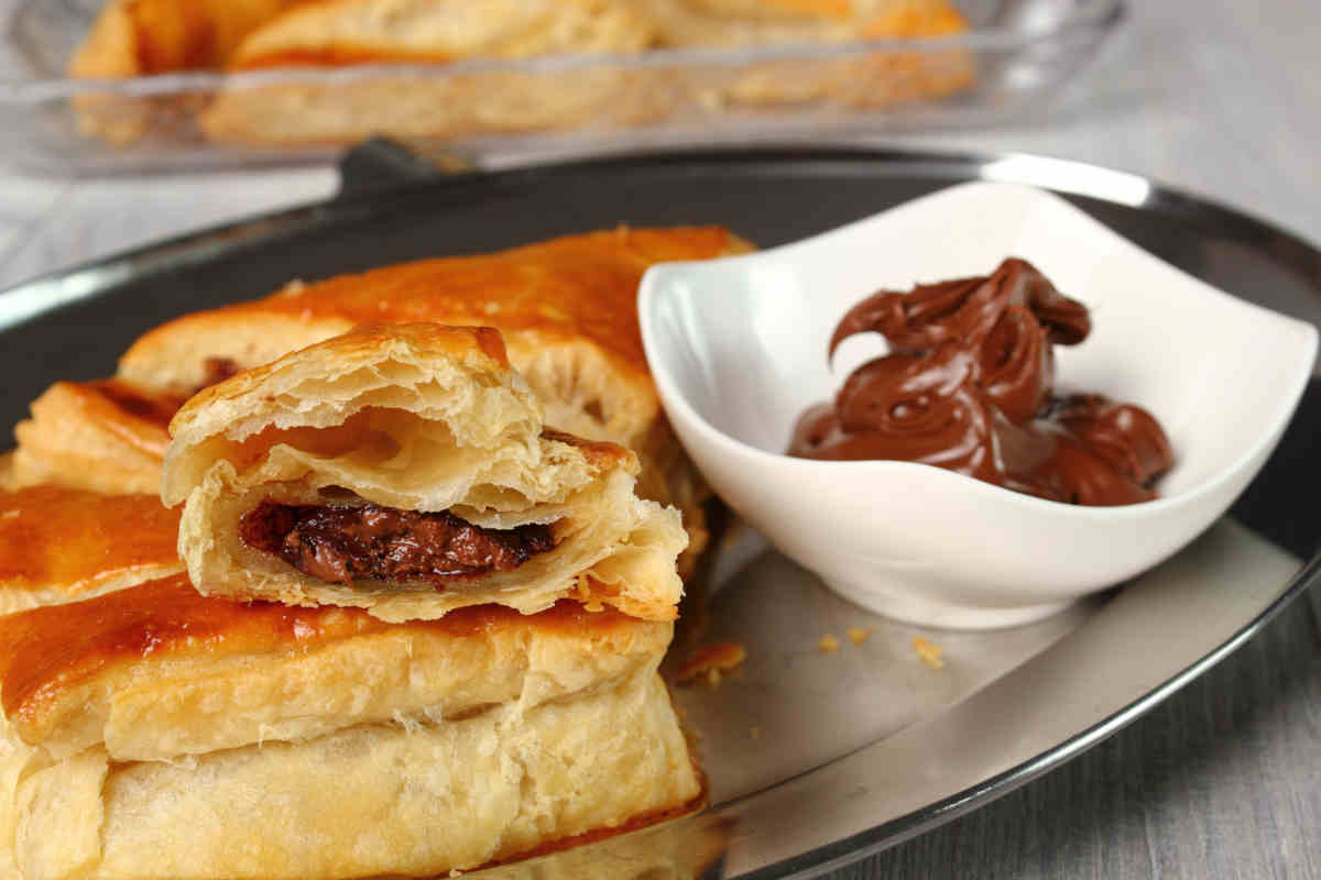 vassoio con sopra dolci di pasta sfoglia e nutella con ciotola di crema