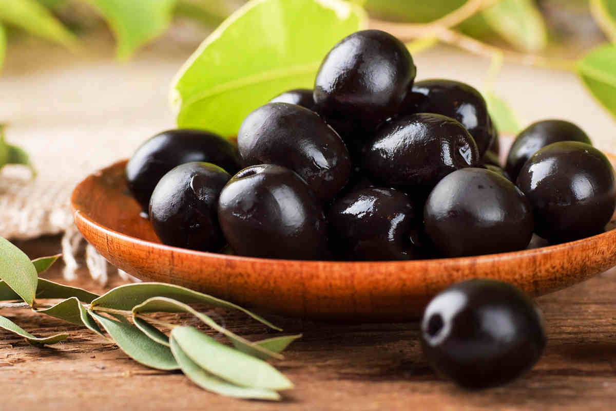 ciotola in legno con olive nere e foglie di alloro