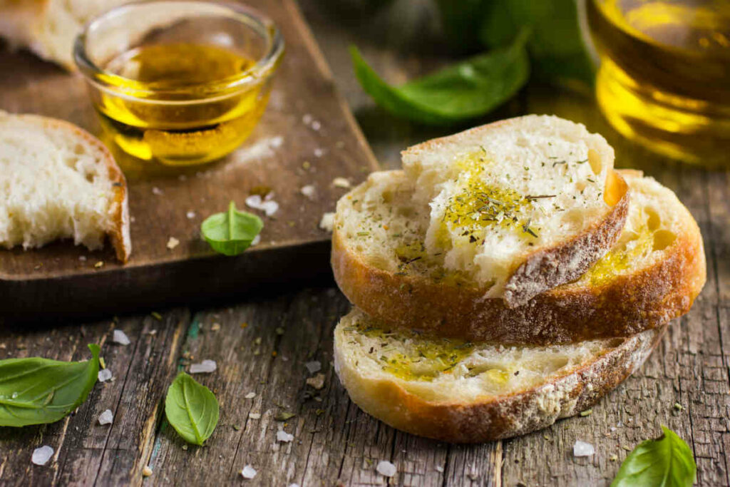 tagliere con fettine di pane condite con olio e erbe aromatiche