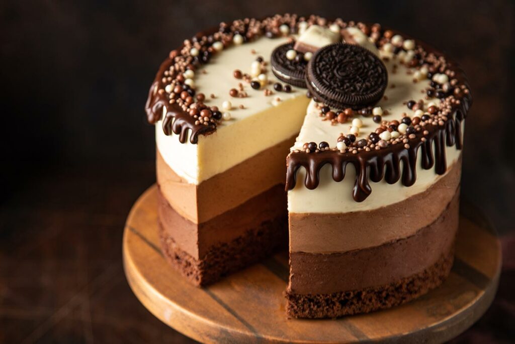 Tagliere di legno con sfondo scuro con sopra una torta ai tre cioccolati